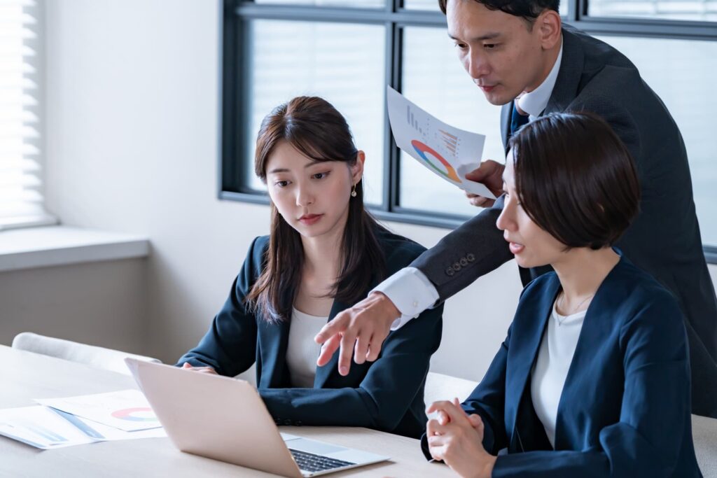 パソコン画面を見て話し合う上司と女性社員2人